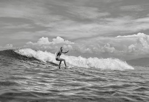 Grayscale Photo of a Woman Surfing