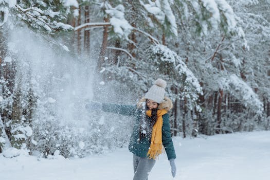 Woman in winter clothing enjoying snow in a forest, capturing the essence of playful winter fun.