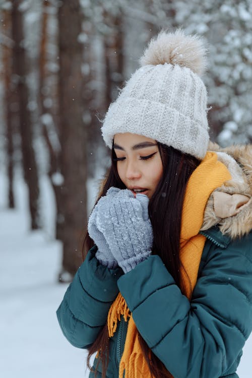 Woman in Gray Knitted Beanie standing on Snow Covered Ground