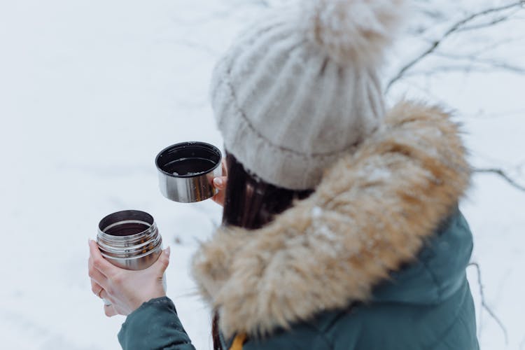 Back View Of A Person Holding A Thermos With Tea