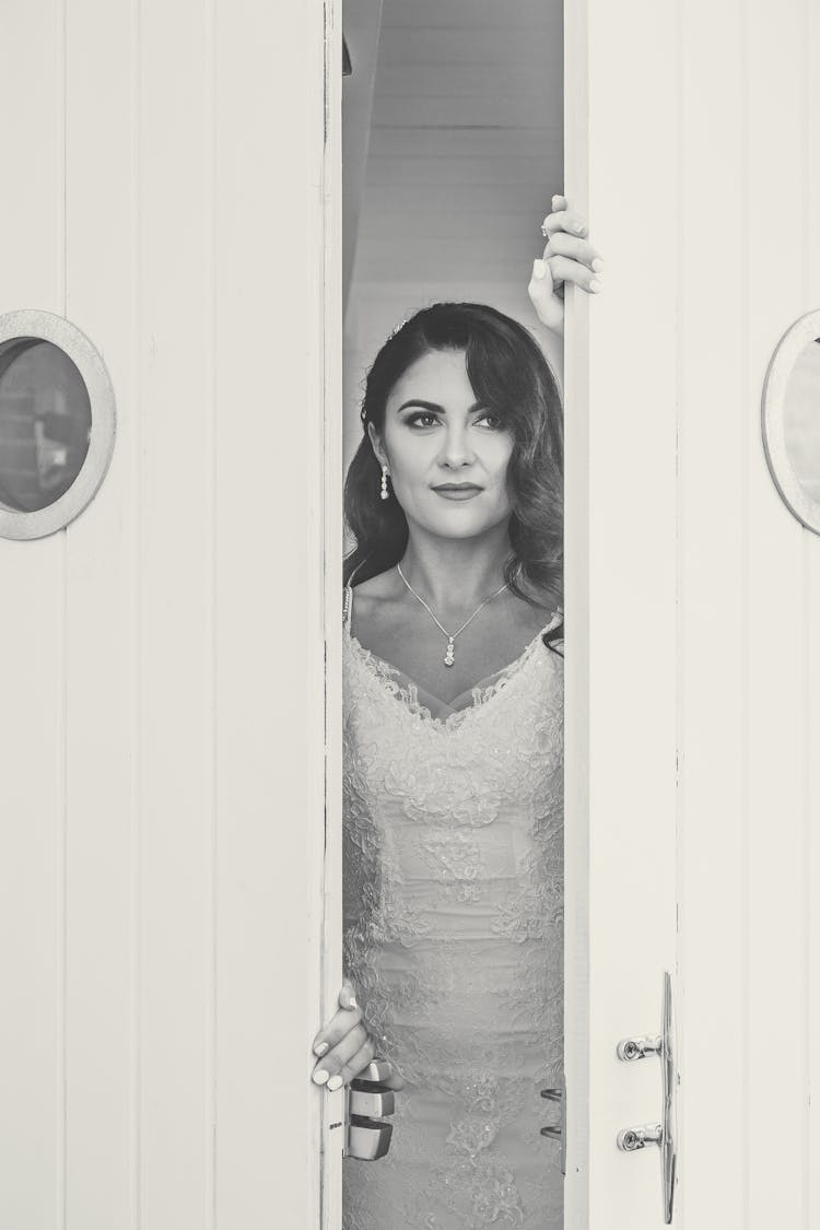 Elegant Young Ethnic Bride In Wedding Dress Opening Door And Looking Away