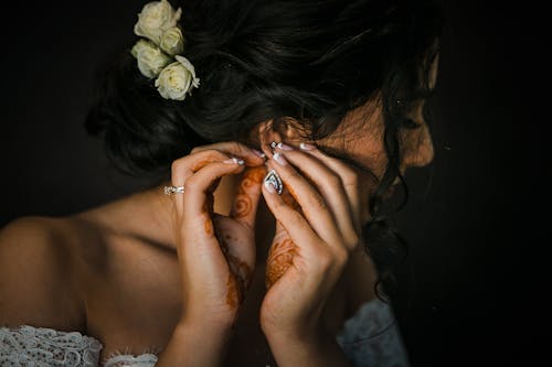 Free Crop anonymous ethnic bride with mehendi on hands and roses in hair preparing for wedding on black background Stock Photo