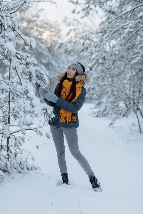 A Woman in Gray Winter Jacket Standing on a Snow-Covered Field