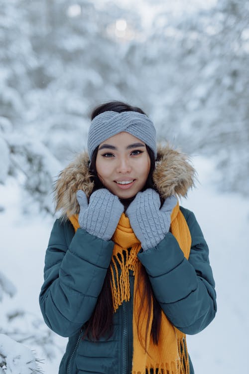 A Woman in Gray Winter Jacket Standing on a Snow-Covered Field