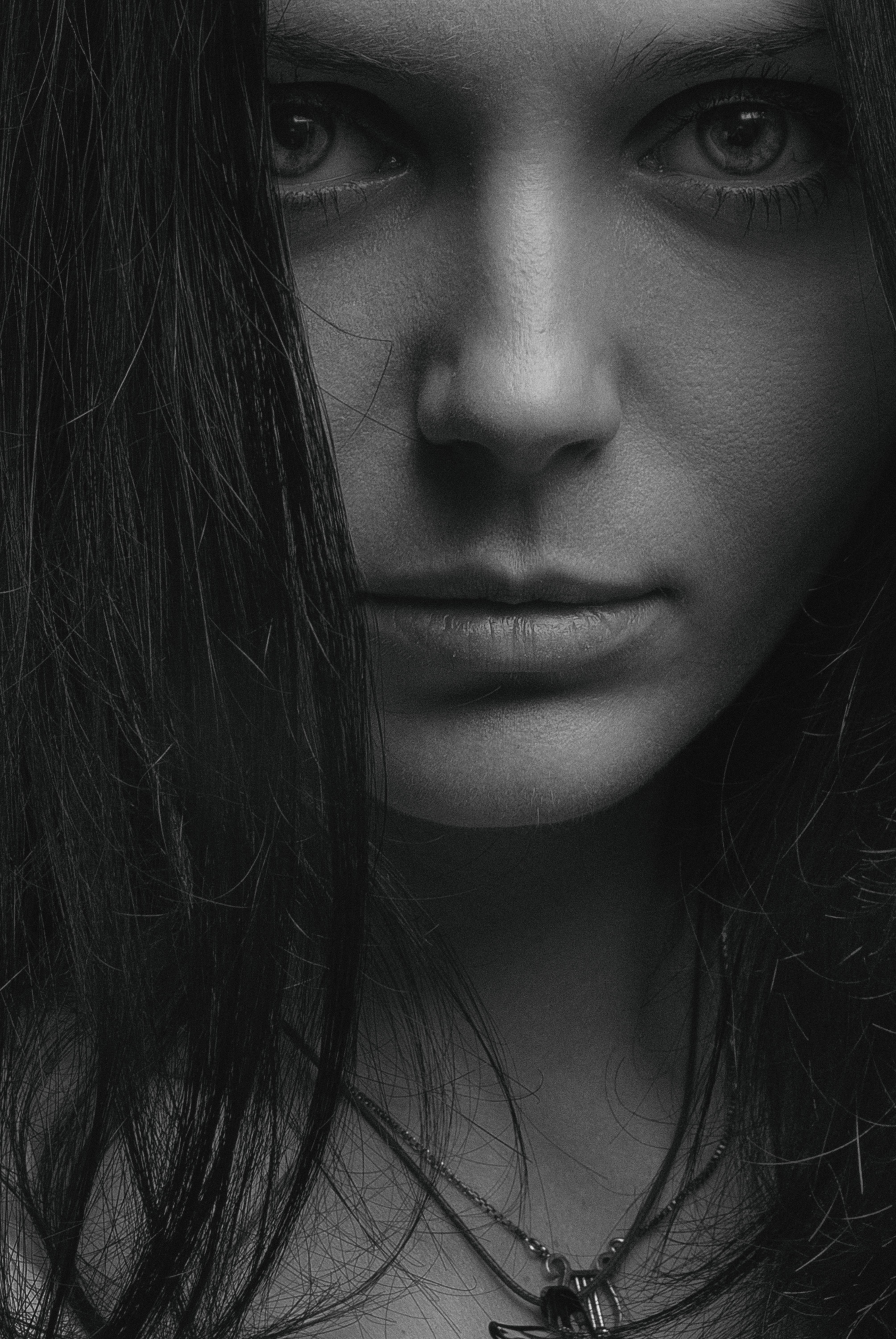 Close-up black and white portrait of a woman with intense gaze, creating a moody atmosphere.