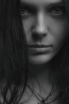Close-up black and white portrait of a woman with intense gaze, creating a moody atmosphere.