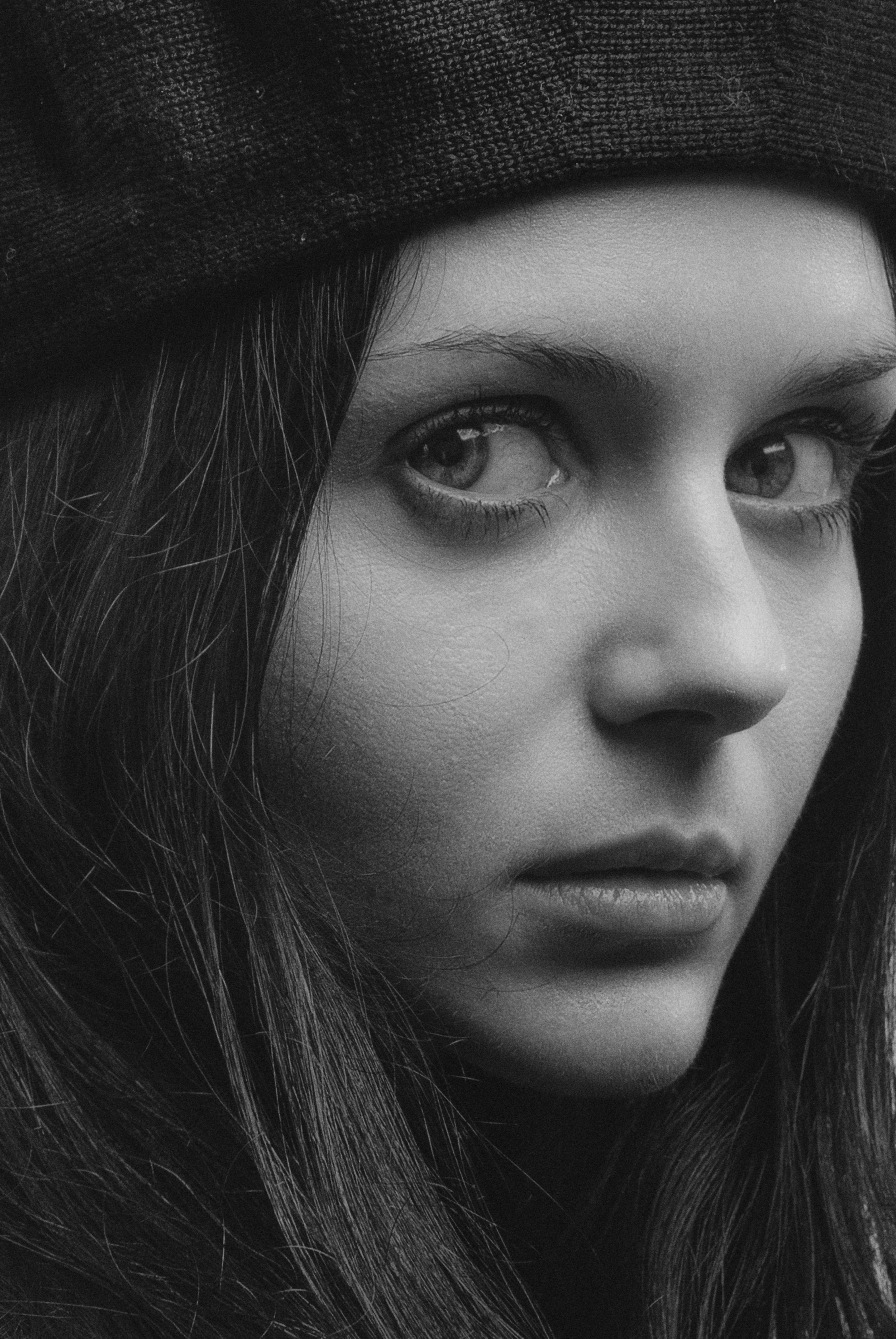 Black and white close-up portrait of a woman in Kyiv, Ukraine, wearing a hat.