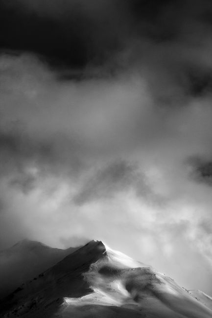 A moody black and white photo of a snow-capped mountain peak in Kamchatka, Russia.