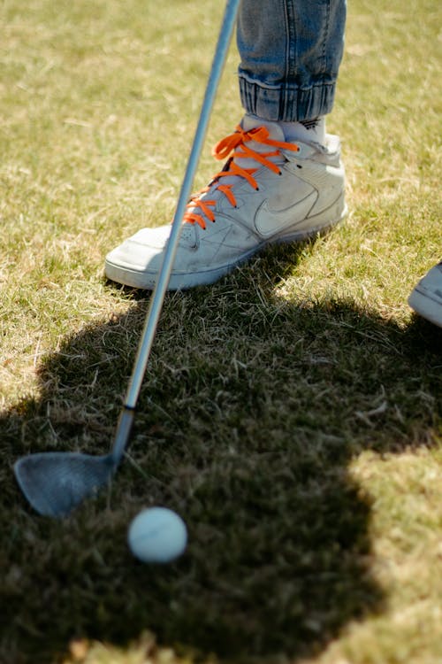 Golf ball on dry grass near player