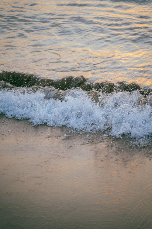 Free Serene wave washing over sandy beach at sunset, perfect for tranquility themes. Stock Photo