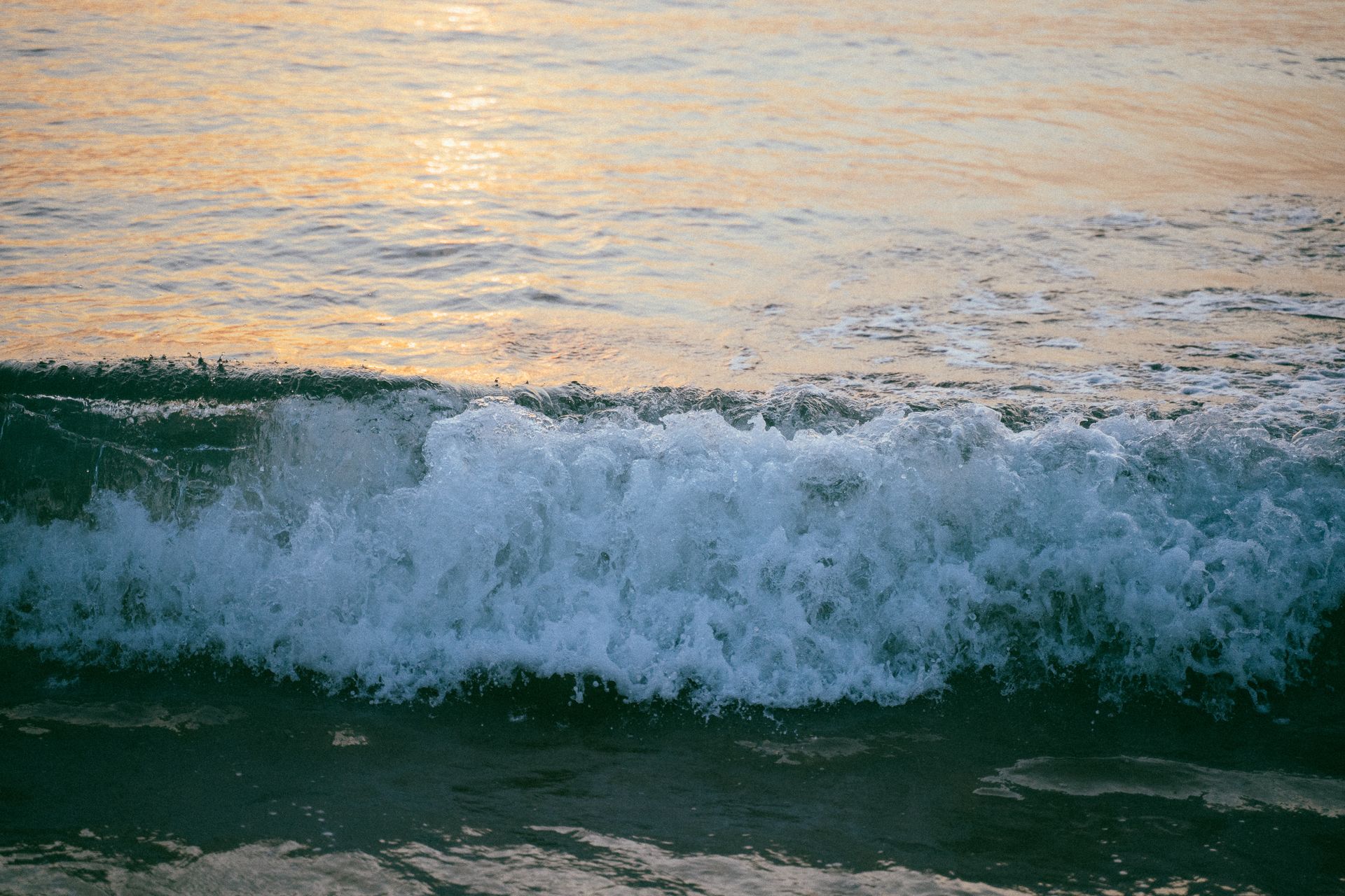 Tranquil ocean waves crashing gently on the shore at sunset.