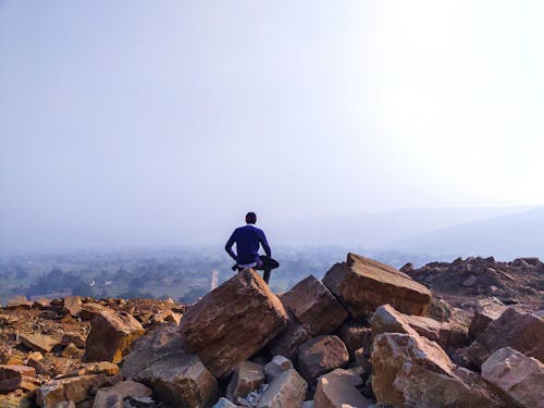 Back View of a Person Sitting on a Rock