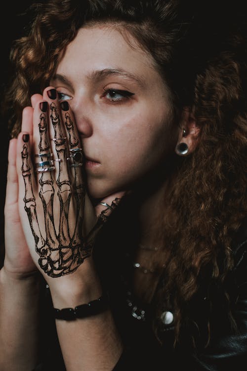 Thoughtful young tattooed lady praying and looking away