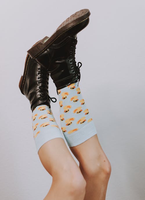 Free Raised legs of crop faceless person in stylish boots and socks Stock Photo