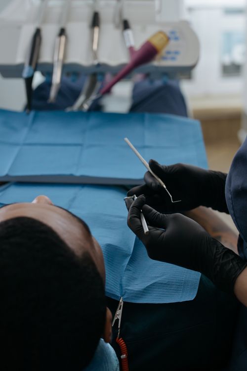 Free Dentist in black gloves performing dental checkup in a clinic setting with patient. Stock Photo