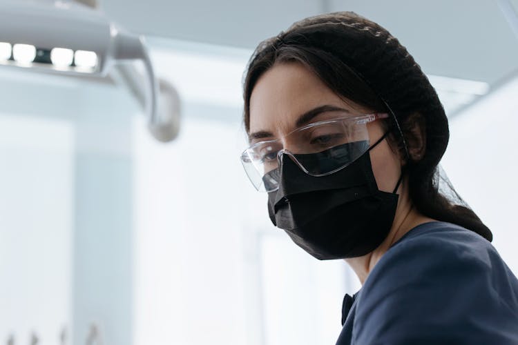 Close-Up Shot Of A Dentist Wearing Black Face Mask And Protective Goggles