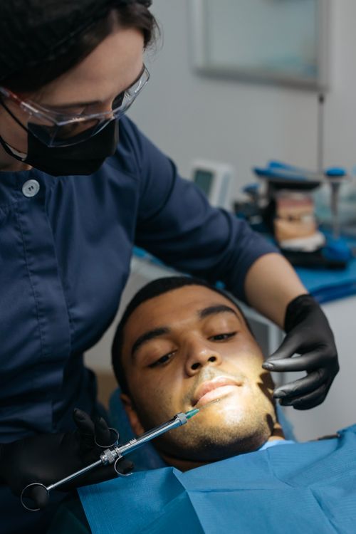 Free Close-up of a dentist administering anesthesia to a male patient during a dental checkup. Stock Photo