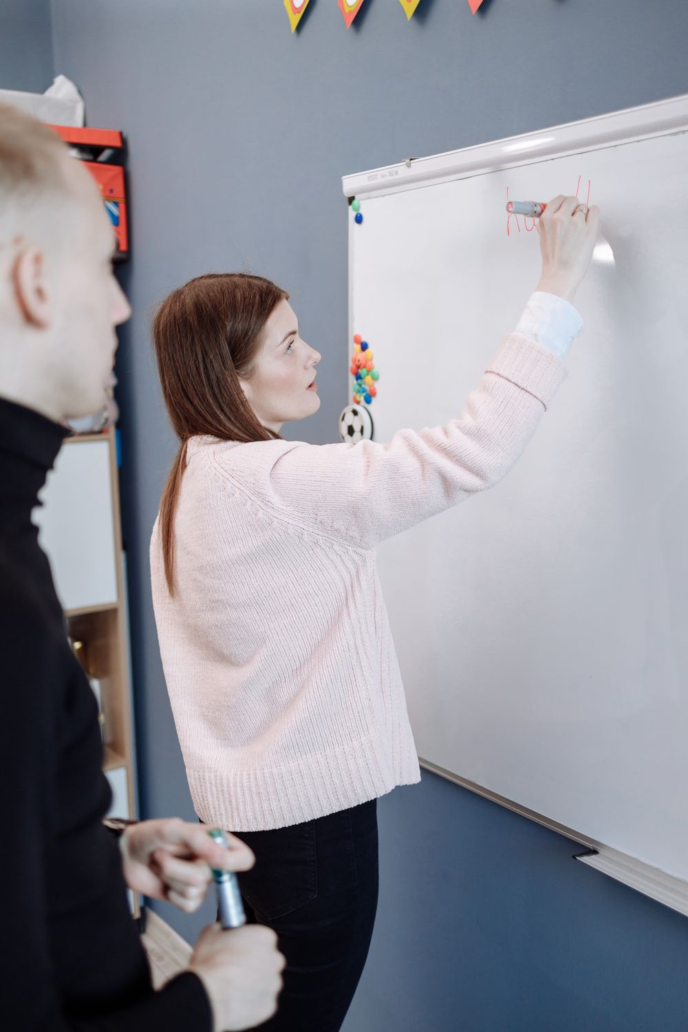 Formatrice ecrivant au tableau blanc lors d une session de formation pour adultes en salle
