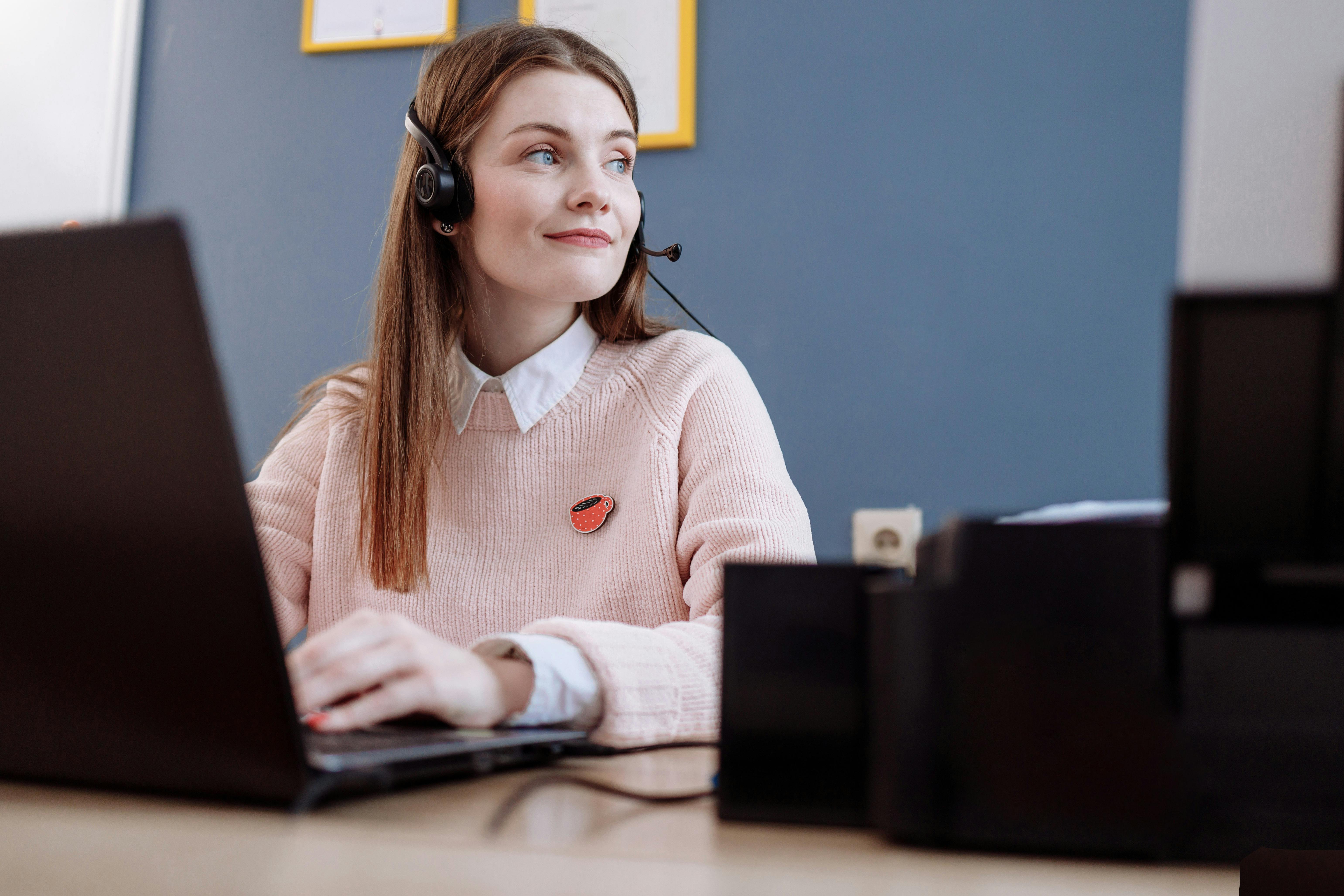 woman in pink sweater using laptop