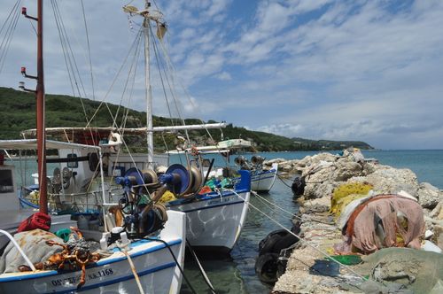 Free Fishing boats moored at a scenic harbor with rocky shoreline on a sunny day. Stock Photo