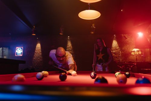 Free Two people enjoying a thrilling game of pool at a lively bar. Stock Photo