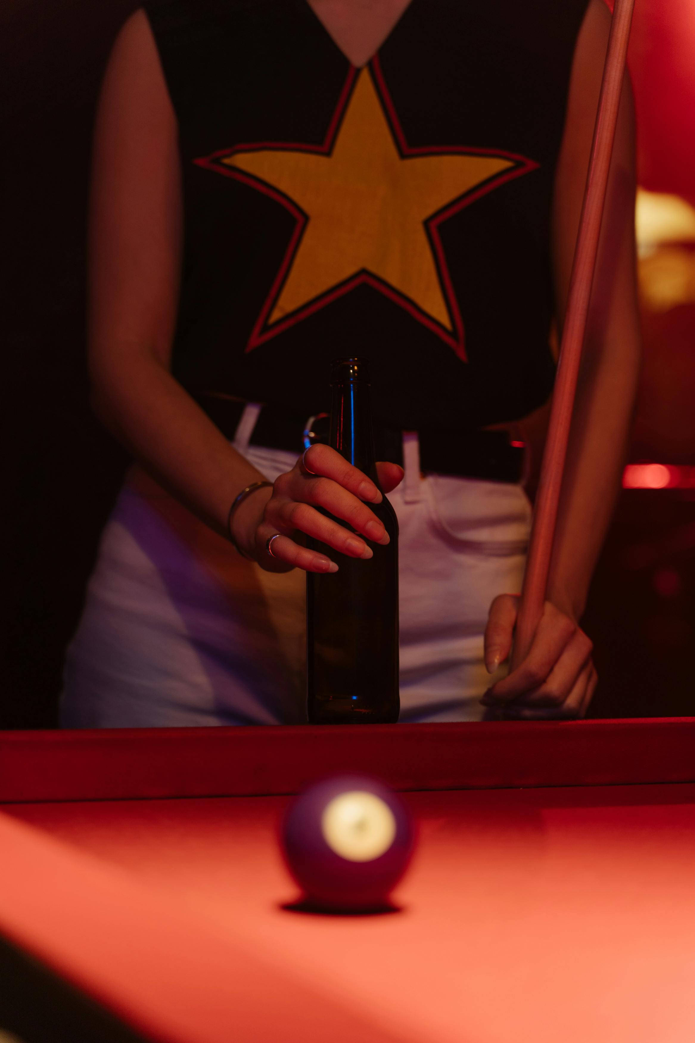 woman in black top holding a beer bottle