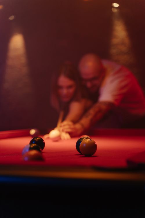 Free A couple focused on a billiards shot with a blurred background for dramatic effect. Stock Photo