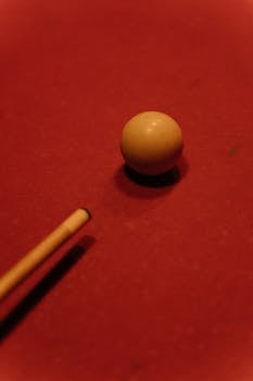 A cue ball positioned on a red billiard table, perfect for billiards enthusiasts.