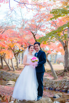 A joyous couple posing for wedding photos in a vibrant autumn forest.