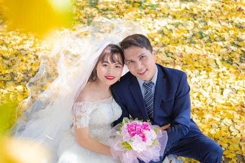Bride and Groom Sitting Outdoors in Autumn and Smiling Posing for a Wedding Photoshoot