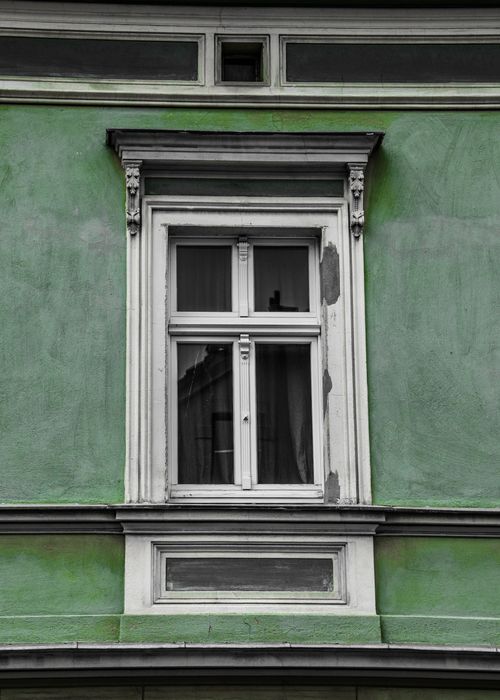 Free A classic architectural facade featuring a vintage window with green detailing. Stock Photo