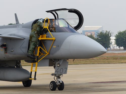 A Person in Green Flight Suit Climbing Cockpit