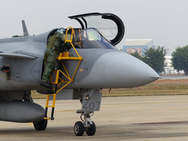 A Person In Green Flight Suit Climbing Cockpit