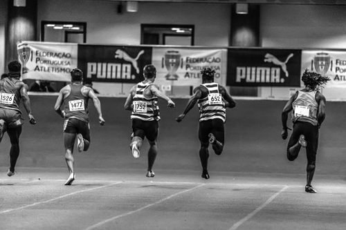 Free Athletes sprinting indoors in a dynamic footrace, showcasing energy and motion. Stock Photo