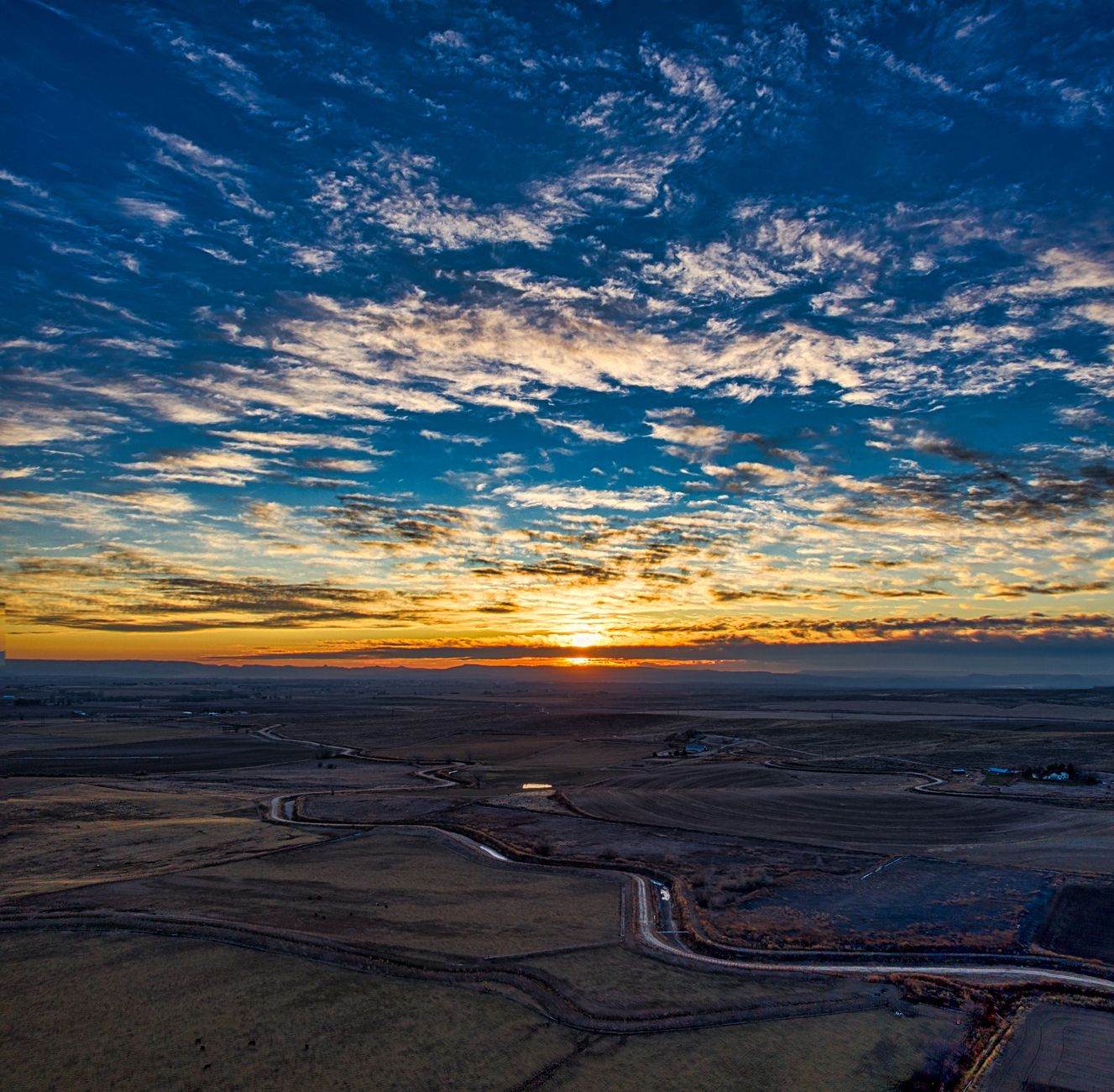 A stunning aerial view capturing the Idaho countryside with a vibrant sunset and vast open fields.