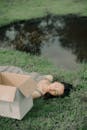 Dreamy woman sleeping on lawn with cardboard box