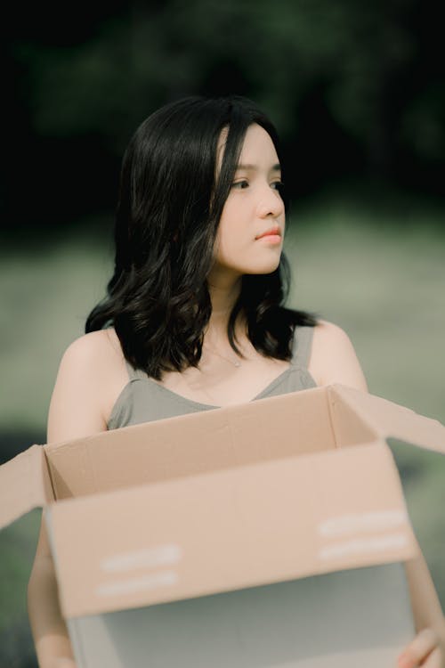 Dreamy woman with carton box on blurred background
