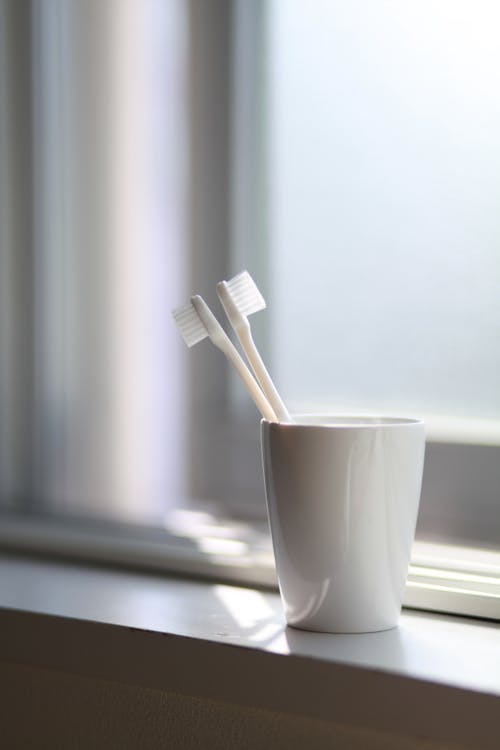 Two White Toothbrush Inside the White Ceramic Cup