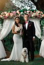 Man in Black Suit and Woman in White Wedding Dress Holding Bouquet of Flowers