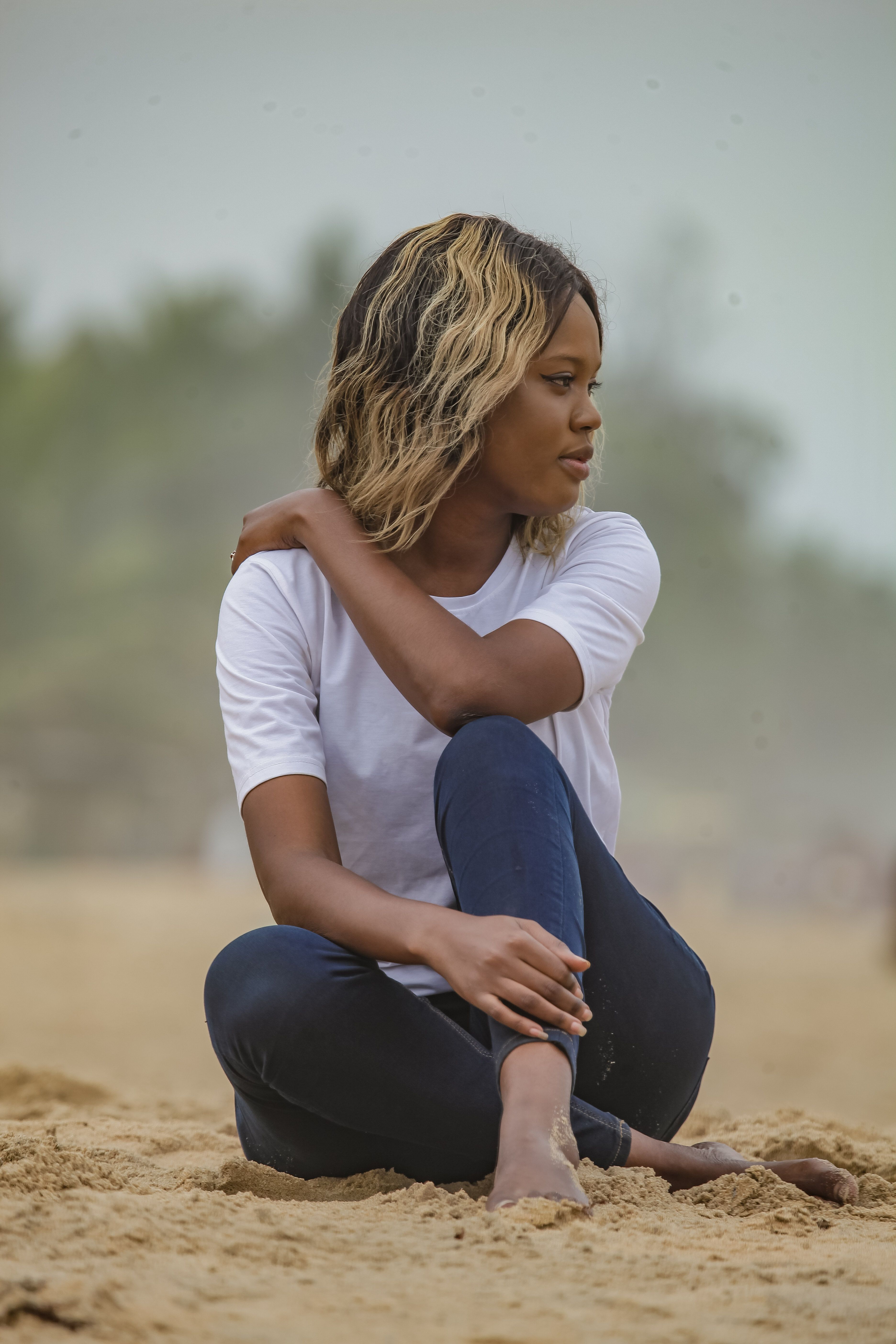 Woman in White Shirt and Blue Pants Sitting on Beach Sand · Free Stock ...