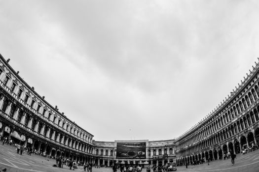 A dramatic fisheye view of St Mark's Square in Venice, capturing its historical architecture in black and white.