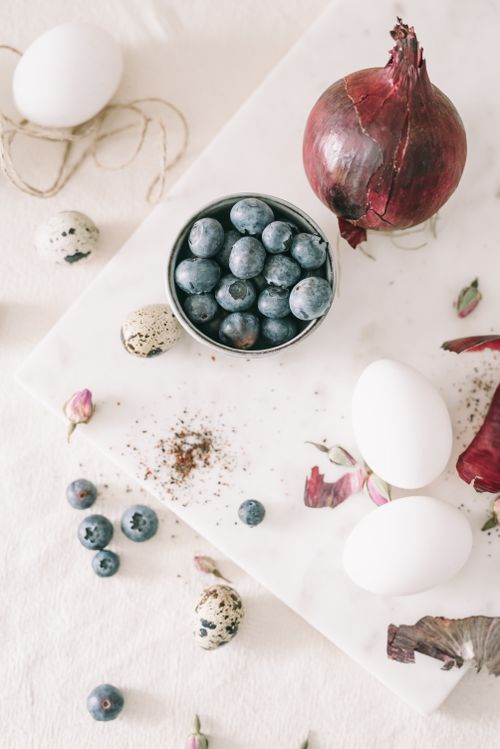 Free Flat lay of Easter-themed still life with blueberries, eggs, and red onion on a white background. Stock Photo
