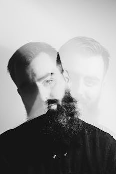 Artistic double exposure portrait of a bearded man in black and white with a modern, conceptual feel.
