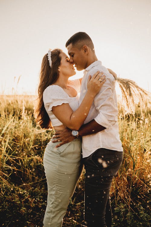 Romantic diverse couple hugging in grassy field