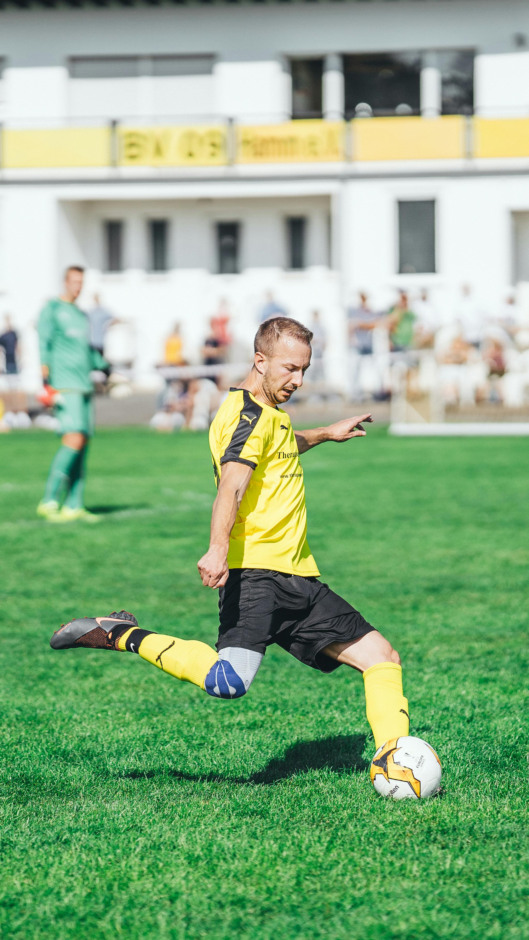 selective focus photo of an athlete kicking a football