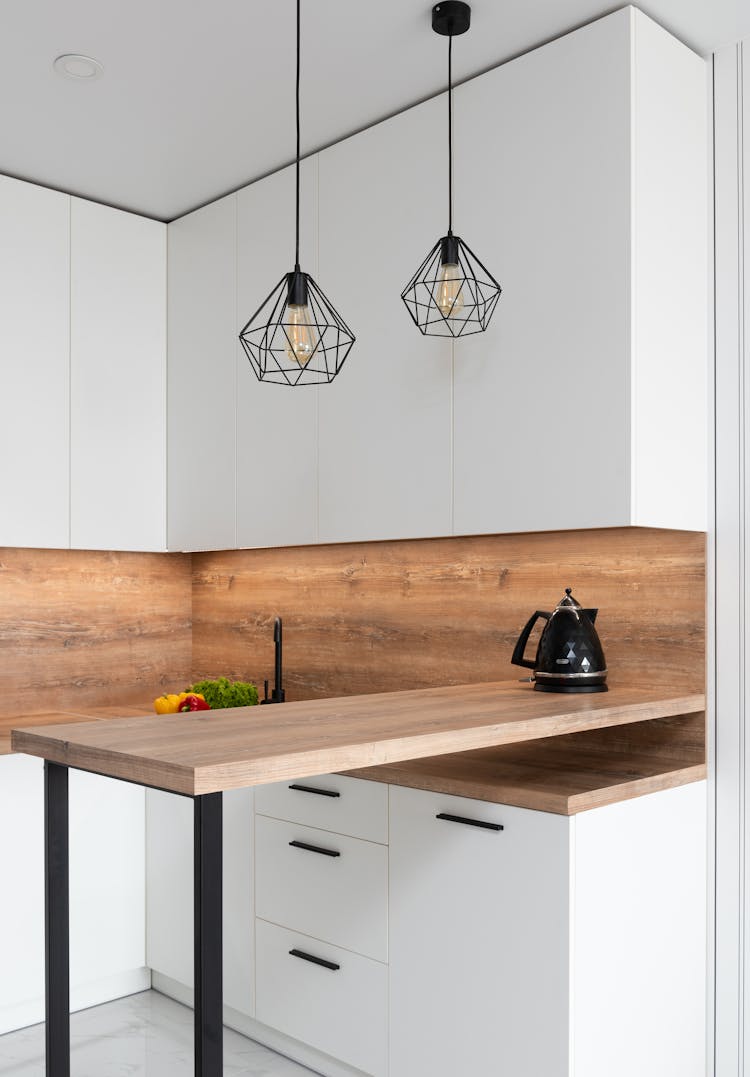 Geometrical Shimmering Lamps Hanging Over Wooden Table Of Kitchen