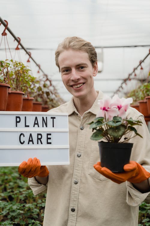 Man Holding A Potted Plant And A Sign