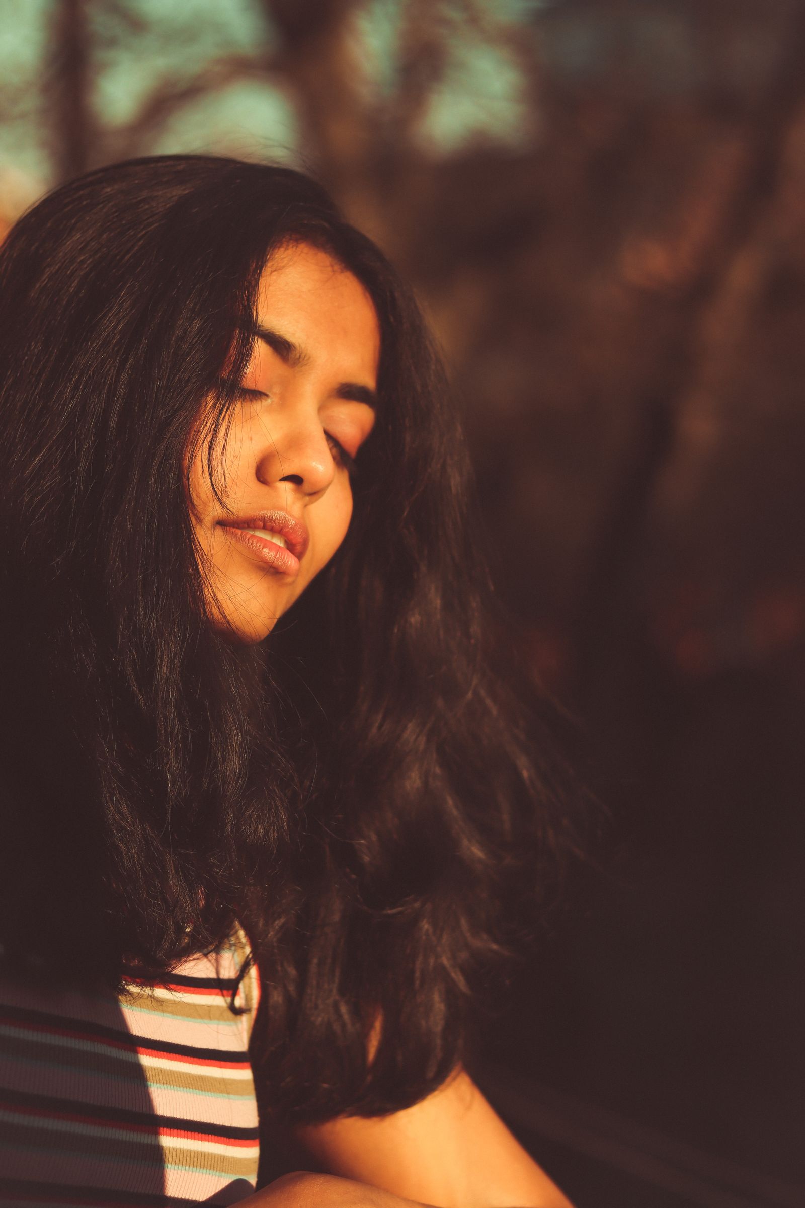 Close-up portrait of a woman with her eyes closed in warm golden light