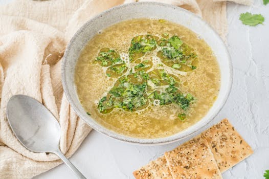 Close-up of a delicious soup garnished with fresh herbs, served with crackers.