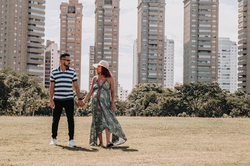 Man and Woman Standing at a Park Near City Buildings